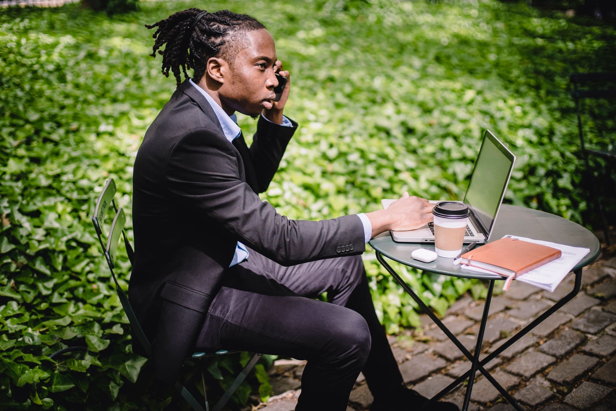 Freelancer belt zelfverzekerd op een terras, laptop en koffie binnen handbereik